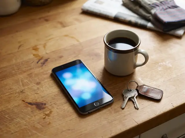 A phone, a coffee mug and truck keys on a kitchen table