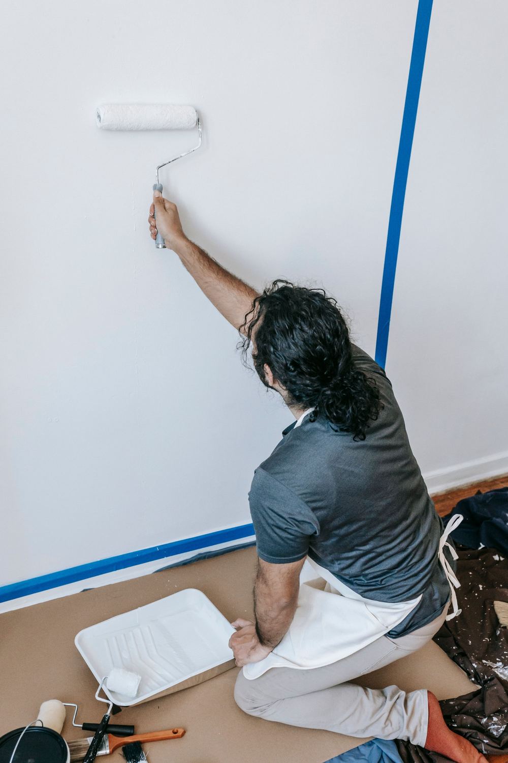 Painter rolling a clean wall next to taped edges
